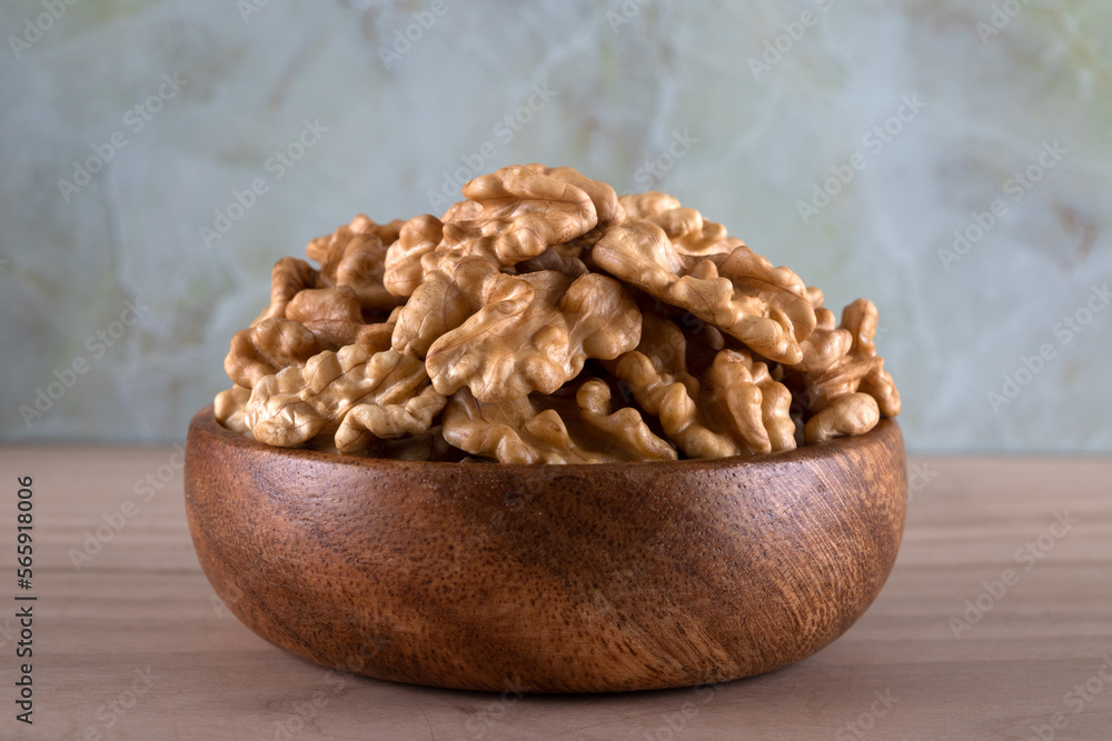 Bowl full of peeled walnuts on a wooden background