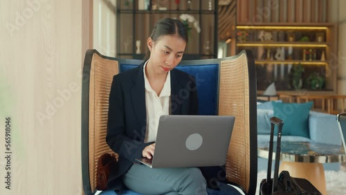 Youth Asia lady passenger formal suit sit on couch eyes focus on computer laptop online work in airline lounge with tea cup wait for transit international airport. Hotel Travel business trip concept. photo