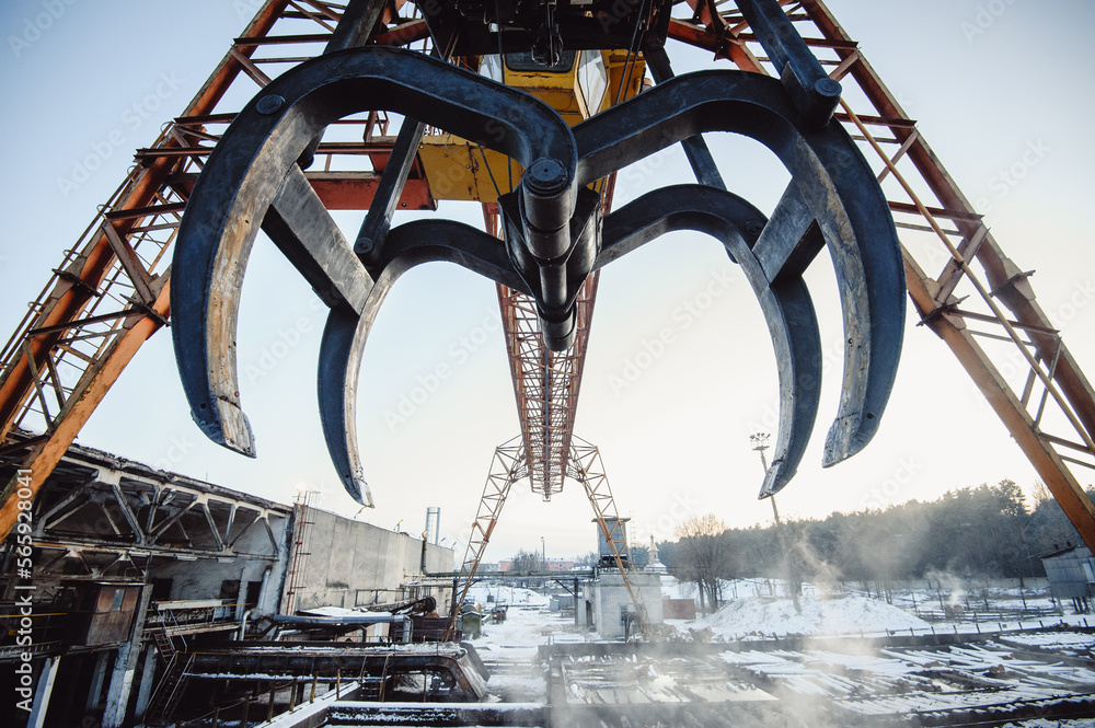 Log crane for wood processing industries. Big grab the crane on the background of a winter sawmill. Log crane for wood processing industries. Big grab the crane on the background of a winter sawmill.