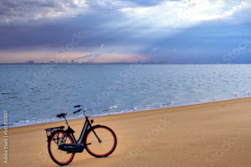 Port building from harbour in Rotterdam. Ladies bike on the beach in depth blur. Landscape of North Sea water and sand after sunrise under moody sky. Netherlands, South Holland, Goeree-Overflakkee.