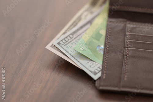 Full grain leather wallet with currency on walnut table