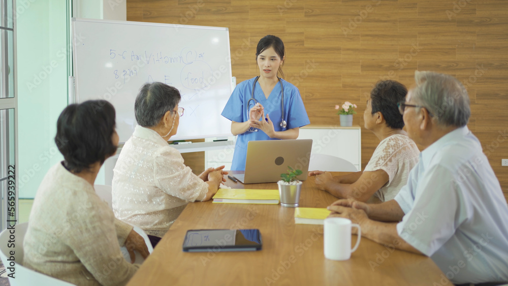An Asian nurse talking to a group of old elderly patient or pensioner people smiling, relaxing, having fun together in nursing home. Senior lifestyle activity recreation. Retirement. Health care An Asian nurse talking to a group of old elderly patient or pensioner people smiling, relaxing, having fun together in nursing home. Senior lifestyle activity recreation. Retirement. Health care