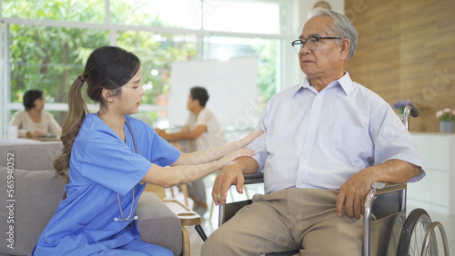 An Asian nurse talking to a group of old elderly patient or pensioner people smiling, relaxing, having fun together in nursing home. Senior lifestyle activity recreation. Retirement. Health care