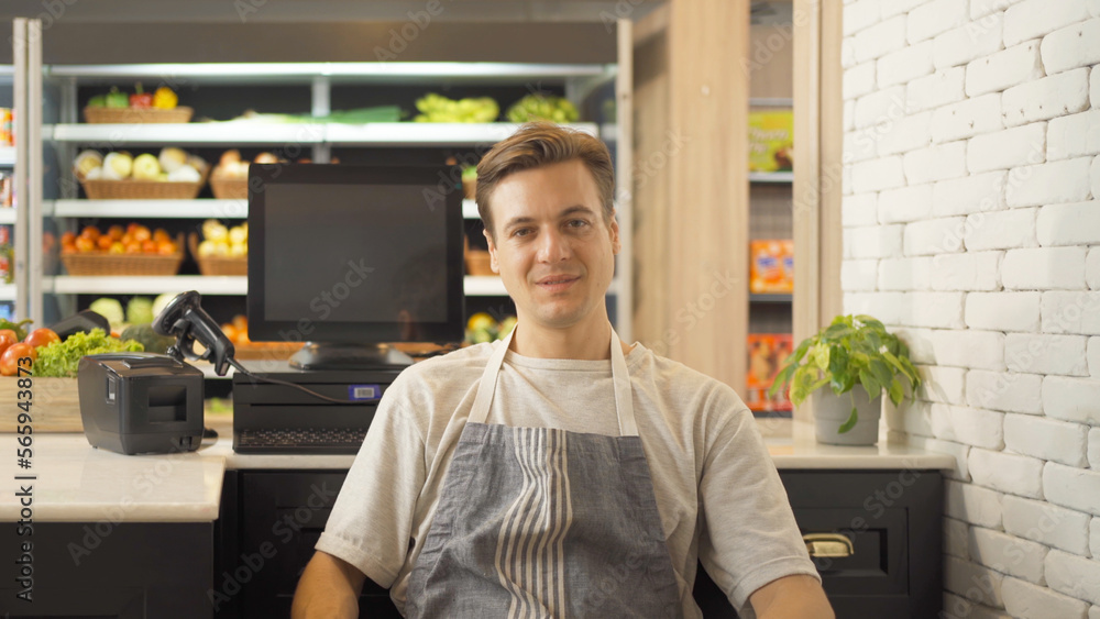 Portrait of a caucasian man working on cashier in a supermarket or retail shop, snacks and food on grocery products shelves. Food shopping. People lifestyle. Checkout business counter service. Worker