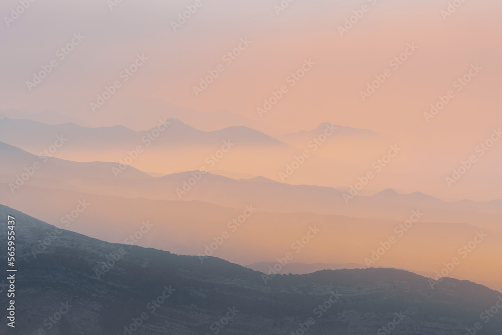 A magical dawn over the Caucasus Mountains with pink layers of mountain ranges and an orange sky