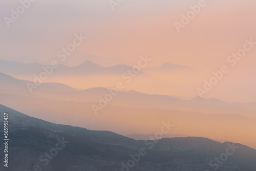 A magical dawn over the Caucasus Mountains with pink layers of mountain ranges and an orange sky © MKozloff