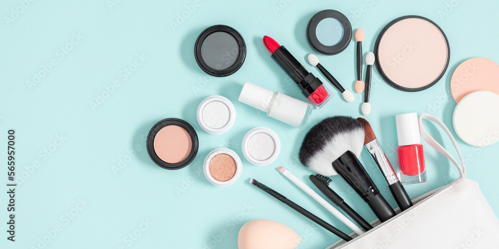 Set of different makeup cosmetics on blue background. White makeup bag and cosmetic beauty products. Flat lay, top view, copy space Set of different makeup cosmetics on blue background. White makeup bag and cosmetic beauty products. Flat lay, top view, copy space