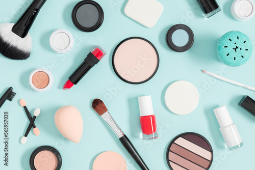 Decorative cosmetics and makeup brushes on blue background. Flat lay, top view, copy space