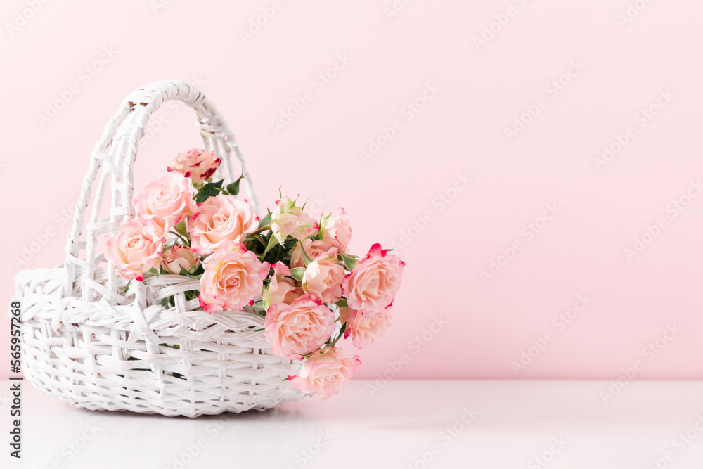 Bouquet beautiful flowers pink roses in white wicker basket on pastel pink background table. Birthday, Wedding, Mother's Day, Valentine's day, Women's Day. Front view