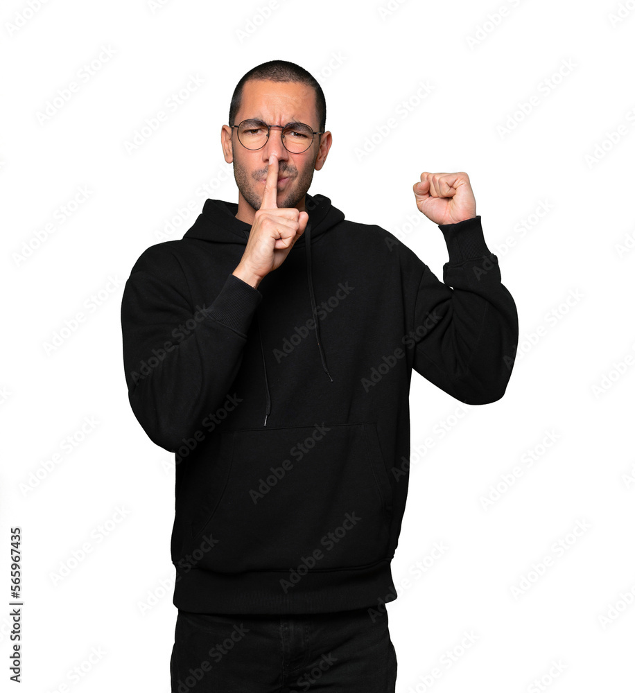 Serious young man asking for silence gesturing with his finger Serious young man asking for silence gesturing with his finger