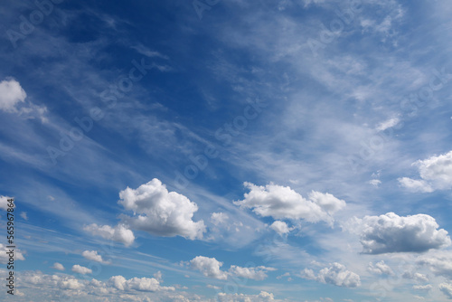 Blue sky with clouds. Spring or summer background. White clouds on the blue sky have a complex pattern. 