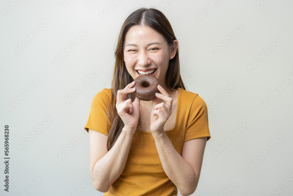 Fototapeta premium Portrait of pretty attractive asian young teenage woman holding chocolate, donut, doughnut, female emotion enjoy sweet. Dieting, diet for loss weight to slim. Isolated on white background, copy space