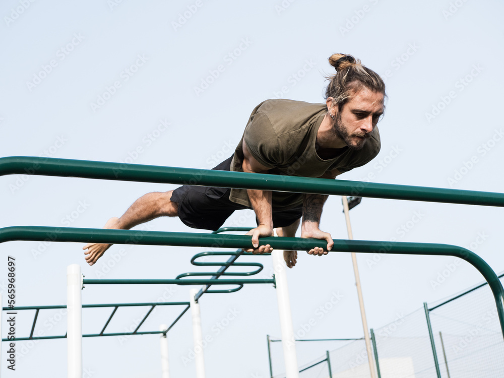 Caucasian man doing elbow lever strength exercise in the calisthenics park