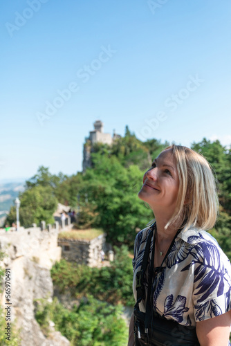 Young beautiful woman smiles against the backdrop of the Guaita Fortress, San Marino, Italy