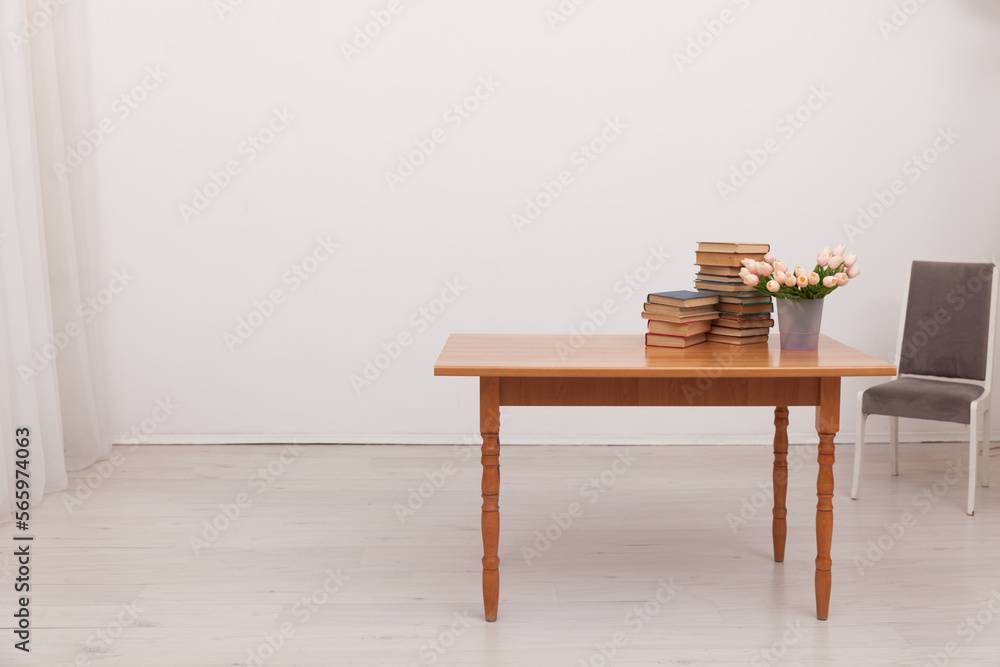 cabinet table with a stack of books and a vase of flowers chair by the table cabinet table with a stack of books and a vase of flowers chair by the table
