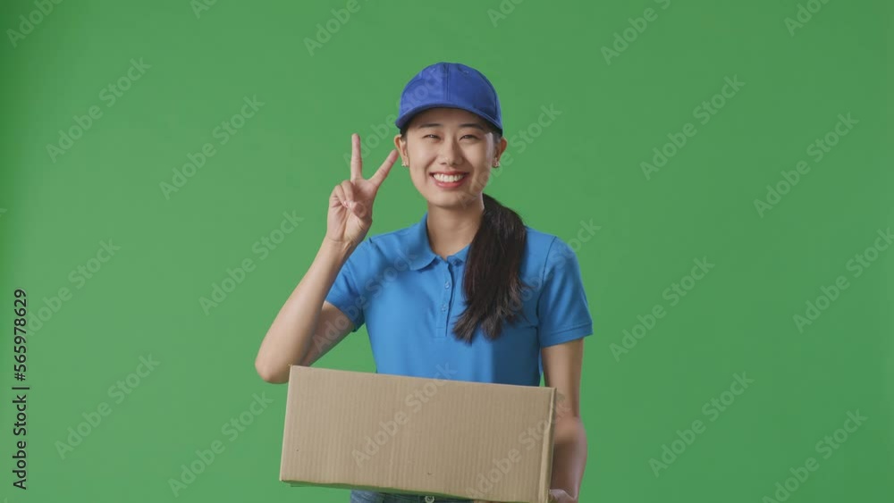 Asian Female Courier In Blue Uniform Showing Gesture Peace And Smiling While Delivering A Carton On Green Screen Background In The Studio
Asian Female Courier In Blue Uniform Showing Gesture Peace And Smiling While Delivering A Carton On Green Screen Background In The Studio