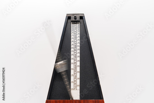 Old fashioned metronome with blurred arm indicating motion isolated on a white background photo