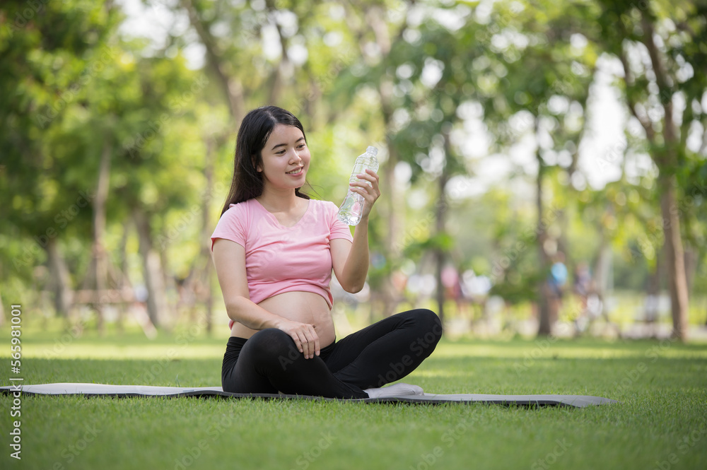 Asian healthy pregnant woman relaxing in the garden and drinking water Asian healthy pregnant woman relaxing in the garden and drinking water