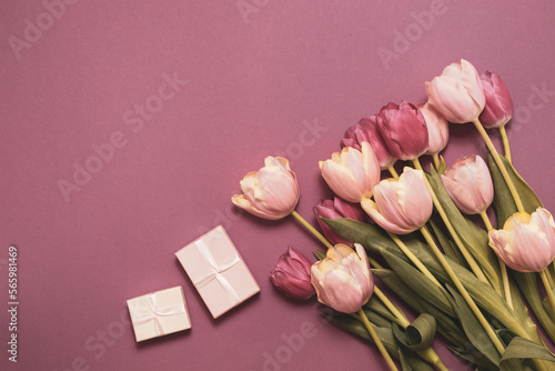 A bouquet of tulips and a box with a gift for the holiday. Beautiful flowers on a pink background. Holidays concept - mother's day, valentine's day, easter