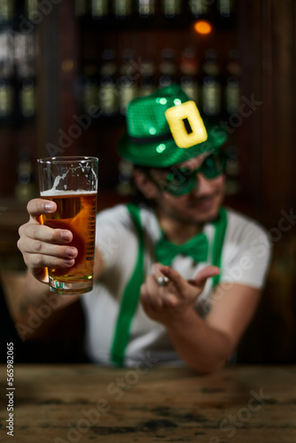 Man with beer in a bar on St. Patrick s Day  wearing a cap  suspenders and bow tie.