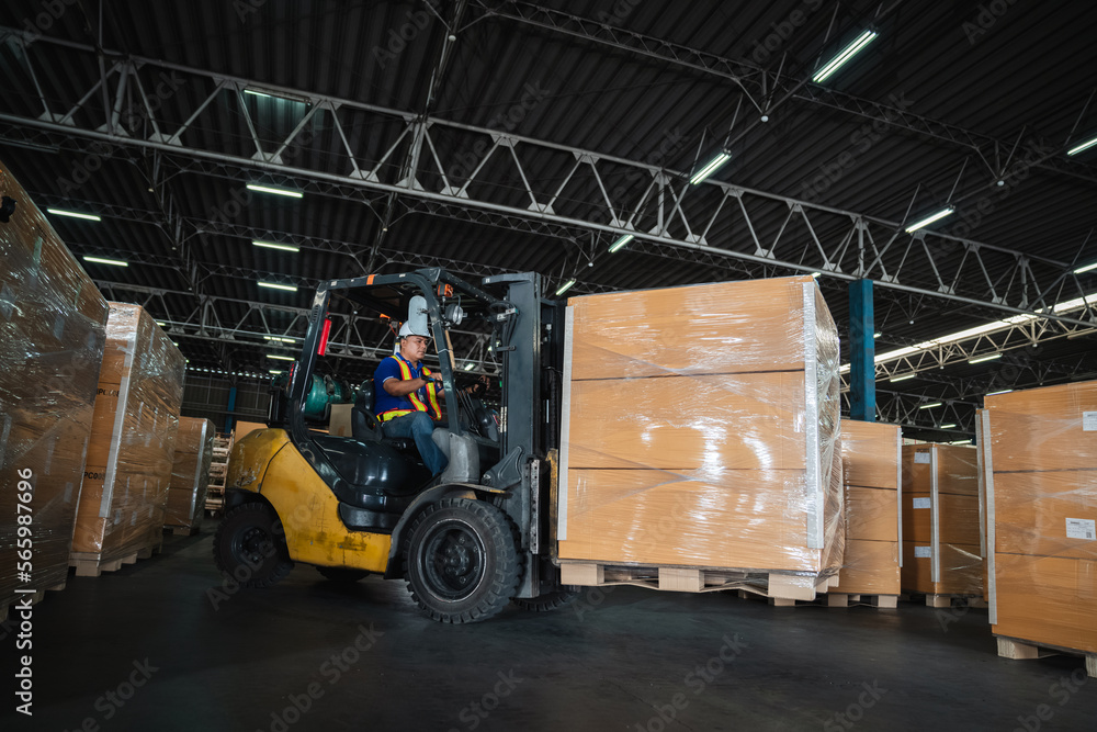 Naklejka premium Warehouse worker workers with forklift in a warehouse. Use forklift operator moves packages. Concept industrial and commercial.