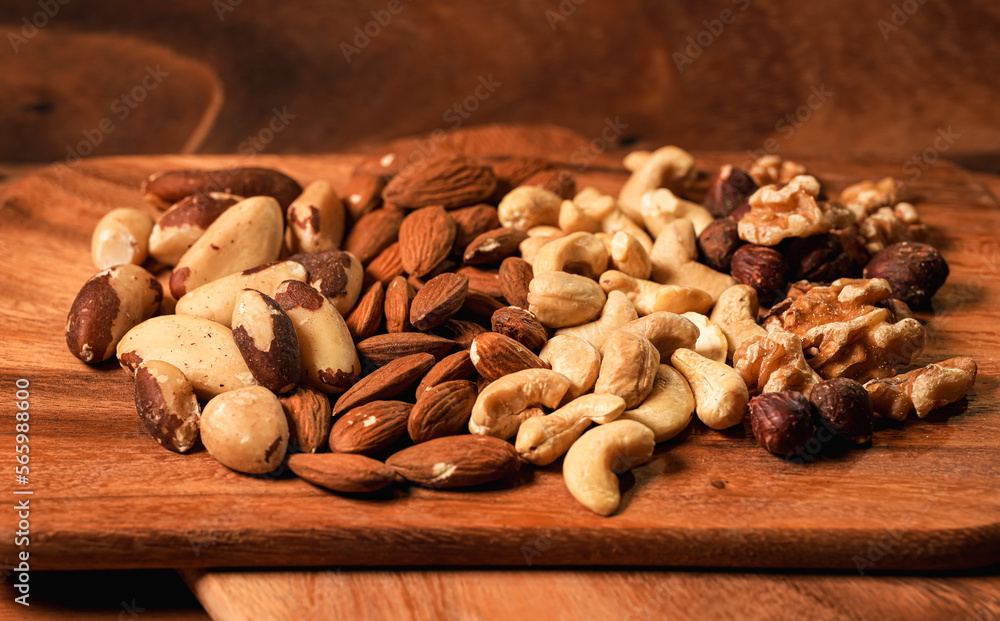Nuts, cashews, almonds and Brazilian nuts. Close up healthy food with proteins. Mix with different types of nuts on a wooden plate. Nuts, cashews, almonds and Brazilian nuts. Close up healthy food with proteins. Mix with different types of nuts on a wooden plate.