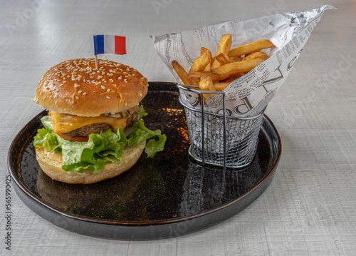 Paris, France - 01 18 2023: Middle East dishe culinary Still Life. Royal Cheese burger with chopped steak, cheddar cheese, fried egg, tomatoes, salad and  french fries accompaniement photo