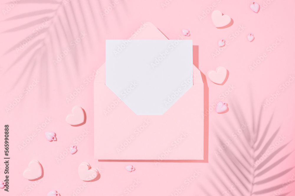 Minimal summer concept. Flat lay photo of tropical leaf shadows, hearts on pastel pink background and open envelope with white card in the middle. Travel holiday card idea. Minimal summer concept. Flat lay photo of tropical leaf shadows, hearts on pastel pink background and open envelope with white card in the middle. Travel holiday card idea.