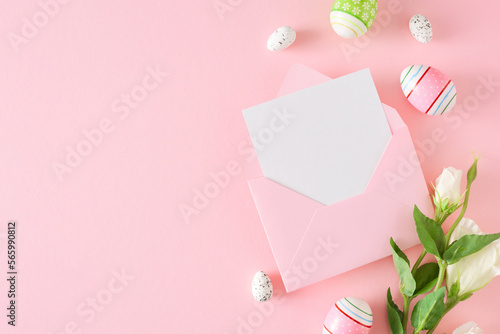 Easter celebration concept. Flat lay composition made of Easter eggs, envelope with letter and flowers on pastel pink background with empty space. Spring holiday card idea. © Goncharuk film