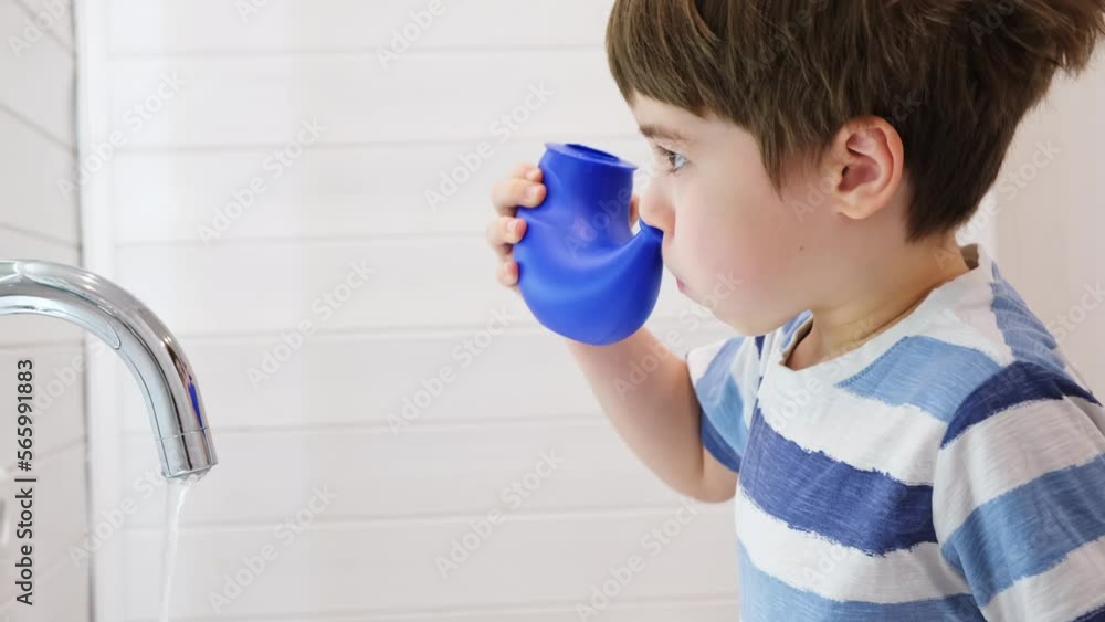 Nasal irrigation. Kid making nasal wash with saline. A young child boy uses the Neti Pot to treat runny nose. Nasal lavage. An Irrigation can. Sinus problem. Nasal allergies. Home bathroom background. Nasal irrigation. Kid making nasal wash with saline. A young child boy uses the Neti Pot to treat runny nose. Nasal lavage. An Irrigation can. Sinus problem. Nasal allergies. Home bathroom background.