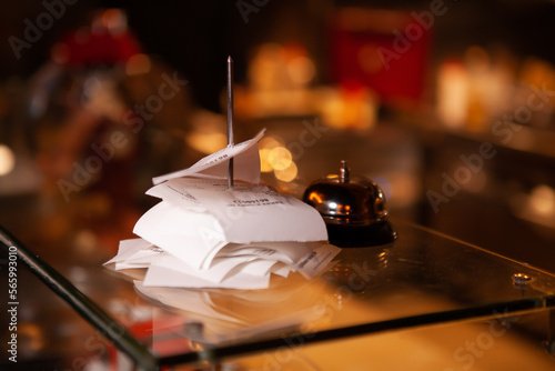 фотографія Checks from completed orders in the bar or restaurant kitchen impaled on a sharp thin iron needle on a stand