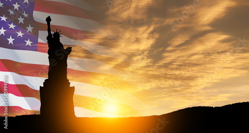 Statue of Liberty with a large american flag and sunset sky on background. Greeting card for Independence Day. USA celebration.