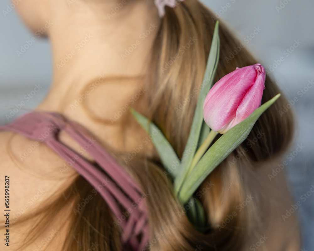 Naklejka premium Delicate pink tulip in long blonde girl's hair