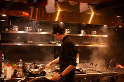 Professional cook. chef in black apron and cap working in restaurant kitchen 