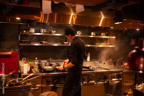 Professional cook. chef in black apron and cap working in restaurant kitchen
