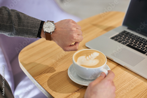 Personal perspecctive view of a businessman cheks the time on his wristwatch while a coffee break
