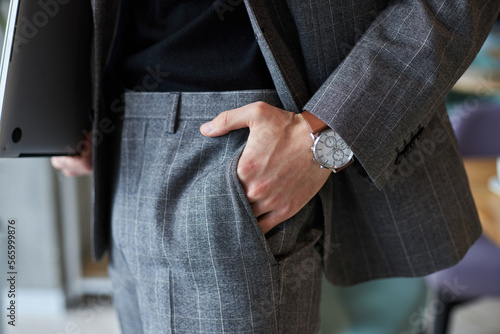Close-up of a businessman in formal suit, holding his hand wearing stylish wrist watch in the pocket