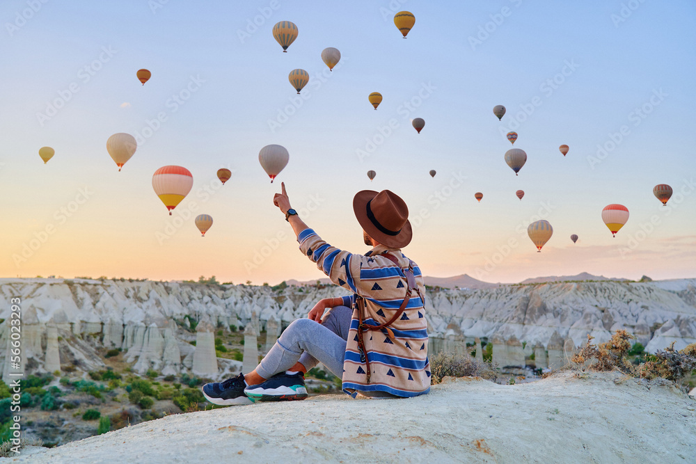 Man traveler vacations beautiful destination in Goreme, Turkey. Fabulous Kapadokya with flying air balloons at sunrise, Anatolia - obrazy, fototapety, plakaty 