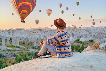 Man traveler vacations beautiful destination in Goreme, Turkey. Fabulous Kapadokya with flying air balloons at sunrise, Anatolia