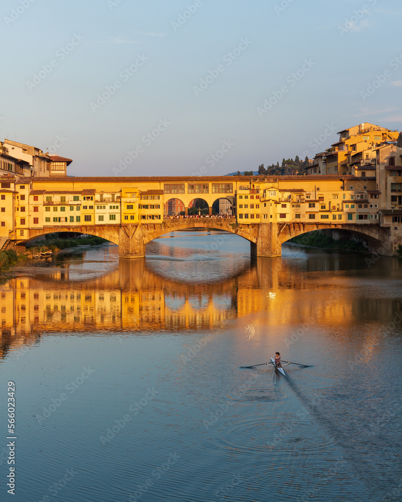 Ponte Vecchio, Florencia al atardecer con una persona pasando por el agua remando en su canoa