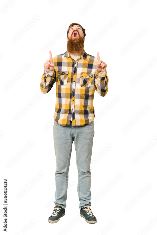 Young adult redhead man with a long beard standing full body isolated pointing upside with opened mouth. Young adult redhead man with a long beard standing full body isolated pointing upside with opened mouth.