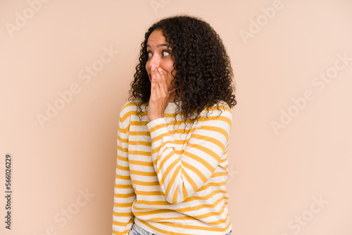 Young african american curly woman isolated being shocked because of something she has seen. © Asier