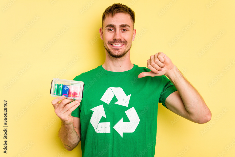 Young man holding batteries to recycle them cut out isolated feels proud and self confident, example to follow. Young man holding batteries to recycle them cut out isolated feels proud and self confident, example to follow.