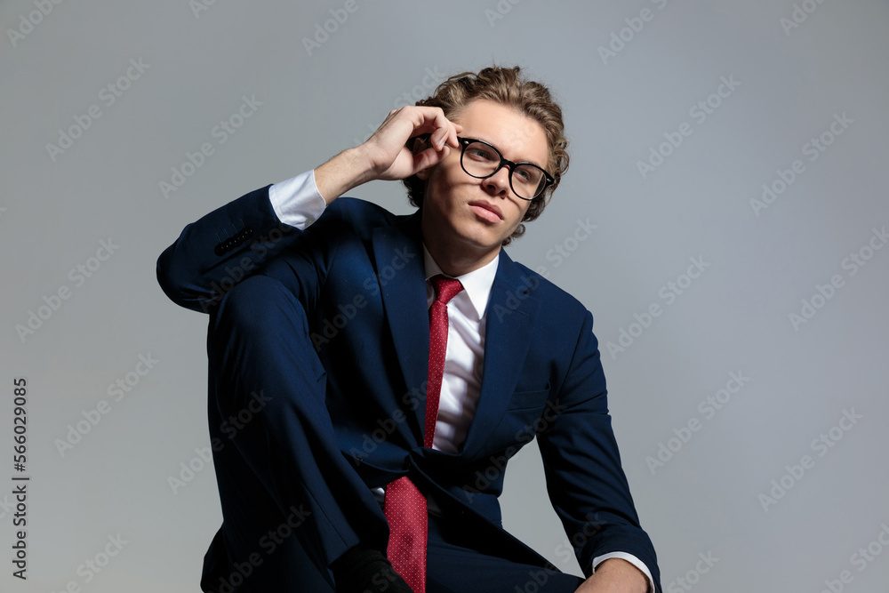 elegant businessman in suit looking away and fixing glasses