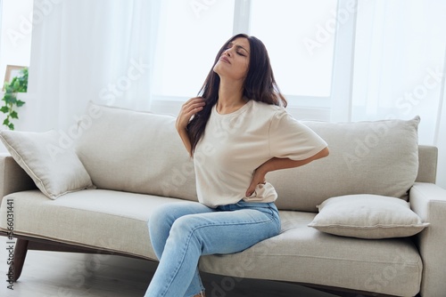 Woman sitting on sofa at home back and lower back pain, protrusion, back problems after 30 years