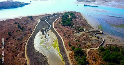 Roads and narrow wooden tourist footbridge among brown spring meadows against turquoise Venetian lagoon in Italy aerial panorama photo