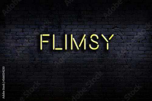 Neon sign. Word flimsy against brick wall. Night view photo