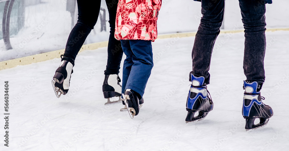 Close-up of family of three wearing skates standing on skating rink they going to skate Close-up of family of three wearing skates standing on skating rink they going to skate