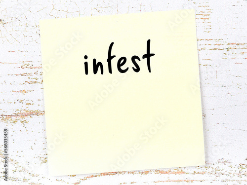 Fototapeta Yellow sticky note on wooden wall with handwritten word infest
