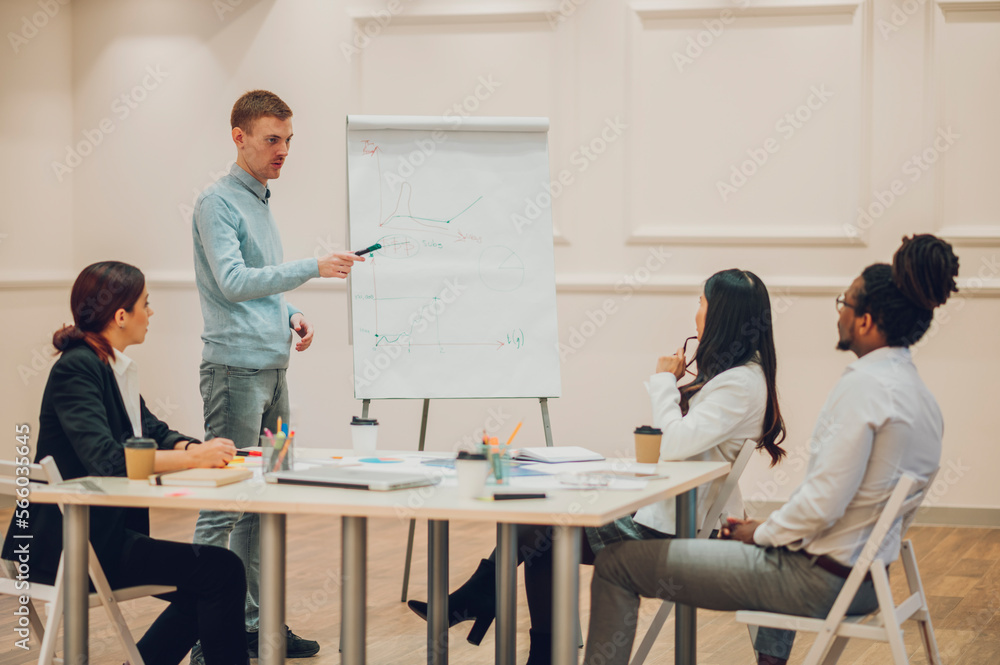 Redhead businessman holding a meeting to his diverse colleagues in an office